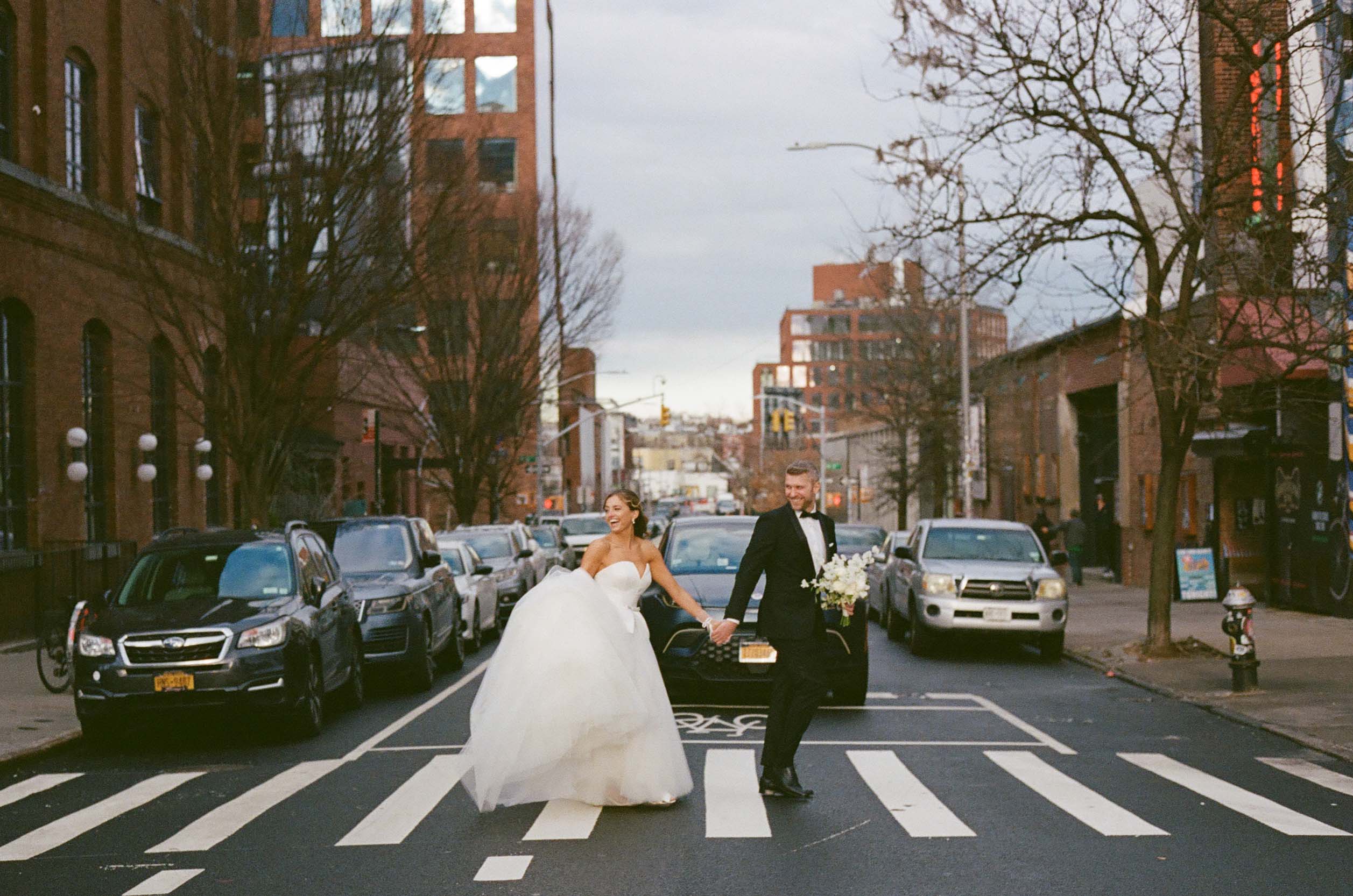 A film photo of a wedding couple crossing the street in williamsburg brooklyn in front of the Wythe hotel. 